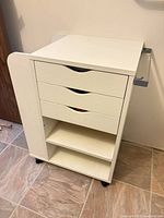 Front view showing three drawers, two shelves, casters