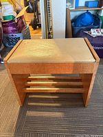 Wood storage bench front view with padded seat and slatted shelf
