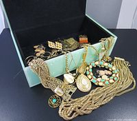 Jewelry box opened with assorted gold tone jewelry pieces