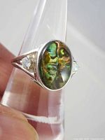 Front angled view showing abalone shell cabochon and one blue topaz