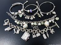 Group shot of all six silver-tone charm bracelets laid out