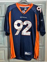 Front view of navy/orange Broncos jersey number 92 on hanger
