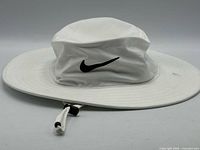 Side view of white Nike Dri-FIT bucket hat showing swoosh logo, brim and chin cord