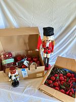 Overview of both nutcrackers, box of red glass ornaments and box of faux fruit picks