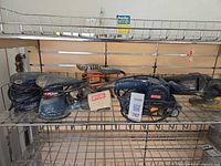 Shelf view of multiple corded Ryobi sanders and Black & Decker disc sander-polisher with cords