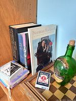 Overall lot showing books, playing-card deck, wine bottle and edge of game board