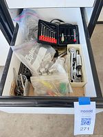 Drawer view showing mixed hand tools, sockets, drill bit case, bags and tray