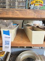 two cream plastic bins on shelf with hardware contents visible