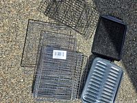 Top view of all grill racks, baskets, black perforated pan and silver drip tray