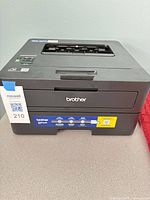 Front and top view of Brother HL-L2460DW printer showing overall condition and installed toner sticker