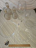 Group shot of all glass items including decanters, plates, bowl, and glasses with scale ruler