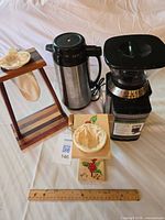 All items: grinder, carafe, cloth filter, two wooden stands displayed beside a ruler for scale