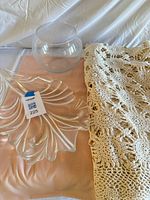 Group showing crochet tablecloth, glass leaf dish, fishbowl vase, peach tablecloth