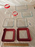 All containers and lids laid out with ruler for scale