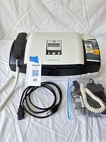 Front view of printer with handset, power and USB cords, bagged telephone cords