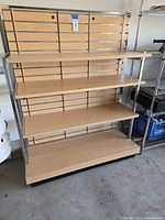 Front view of full shelving unit showing slatwall back, four shelves, chrome frame, black base