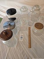 Group shot showing all ten glass jars and assorted lids with ruler for scale