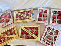 Seven boxed sets of red glass ornaments displayed