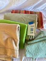 Stack of beige, lime, sage, striped tablecloths with mint napkins