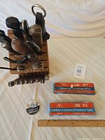 Top angle view of knife block filled with knives and honing steel, two boxed sharpening stones and ruler for scale