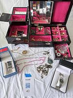 Overview of open jewelry boxes, watches in boxes, loose necklaces and bracelet on cloth