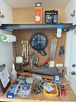 Overall view of workbench with boxed laser level, Exide charger, wall clock and assorted tools