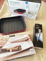 Lot overview showing roasting pan with rack, boxed platters set, boxed corkscrew
