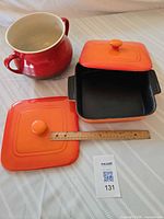 Square casserole with lid, extra lid, and red soup tureen displayed with scale ruler