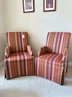 Front view of both striped armchairs showing upholstery, skirted bases and rolled arms