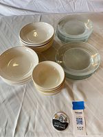 Stacked stoneware bowls and clear glass plates displayed on table