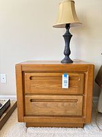 Nightstand with lamp on top, boxed item and prints visible beside