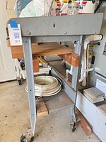 Front view showing metal frame, wood top, lower shelves, casters