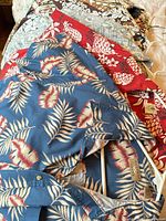 Stack of six patterned Hawaiian shirts on bed