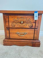 Front view showing full nightstand, drawers, carved design and hardware
