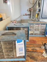 Three blue metal parts organizers on workbench, MaxSold tag visible
