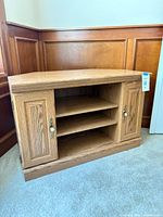 front view of light oak TV stand showing cabinet doors and open shelving