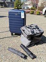 Suitcase, cooler and two umbrellas on driveway