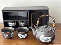 complete tea set displayed with box showing two cups inside compartments, two cups outside, and teapot front