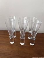 Five clear flutes standing on wooden surface