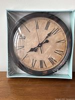 Clock inside shrink-wrapped box showing face and frame