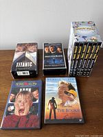 Group shot of all media items: boxed Looney Tunes set, Titanic VHS, Meet Joe Black VHS, Home Alone DVD, The Rookie DVD