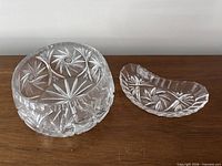 Round pinwheel crystal bowl and kidney condiment dish on wood surface