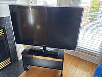 Front view of Samsung TV on black stand with remote visible