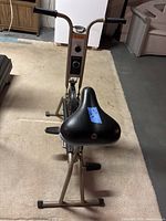 Full view of CCM stationary bike from rear showing handlebars, flywheel, Schwinn seat