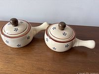 Two lidded cream ceramic onion soup bowls with handles, top view