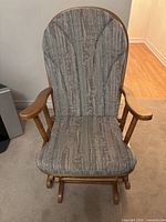 front view of wooden rocking chair showing cushion and spindle arms