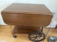 Side view showing drop leaves folded, large spoke wheel, lower shelf