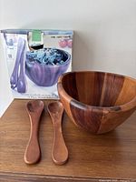 Box, wood salad bowl and two servers on table