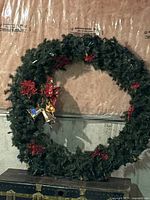 Full view of large decorated wreath leaning against wall