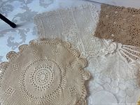 Group of assorted crocheted doilies in neutral tones
